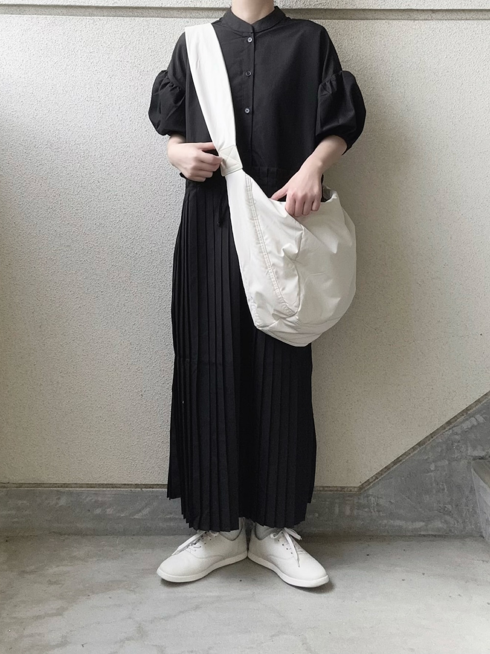 ブラック系のワンピース、ホワイト系のショルダーバッグ、ホワイト系のスニーカーを着用したレディースの春コーディネートの1枚目の写真