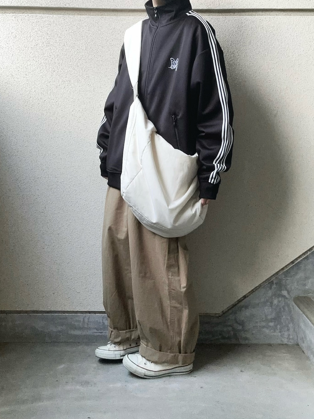 ブラック系のジャージ、ベージュ系のチノパンツを着用したレディースの春コーディネートの1枚目の写真