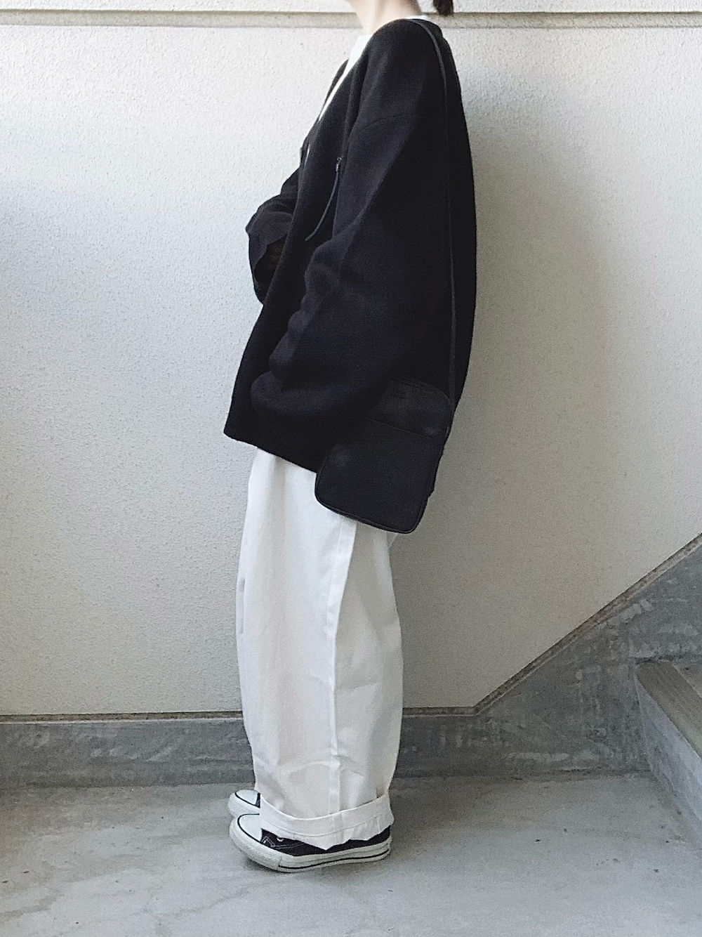 ベージュ系のチノパンツ、ブラック系のカーディガン/ボレロ、ホワイト系のTシャツ/カットソーを着用したレディースの秋コーディネートの1枚目の写真