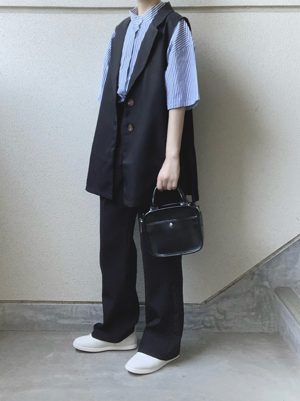 ブラック系のベスト、ブルー系のシャツ/ブラウス、ブラック系のスラックスを着用したレディースの夏コーディネートの1枚目の写真