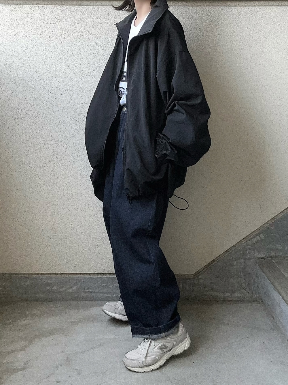 ブラック系のナイロンジャケット、ブルー系のデニムパンツ、ホワイト系のTシャツ/カットソーを着用したレディースの春コーディネートの1枚目の写真