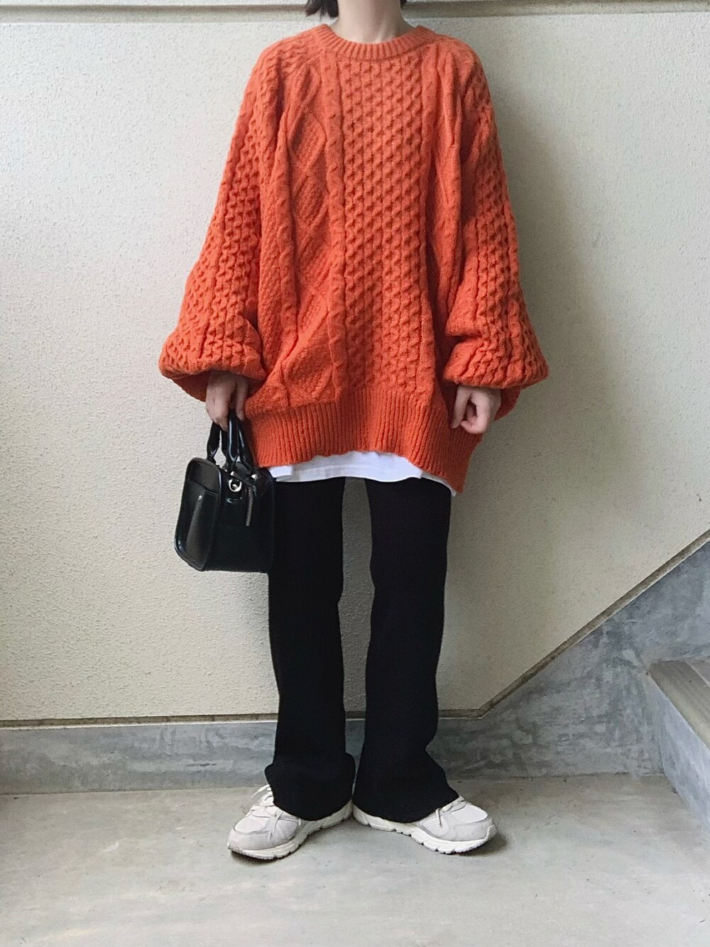 オレンジ系のニット/セーター、ブラック系のその他パンツ、グレー系のスニーカーを着用したレディースの秋コーディネートの1枚目の写真