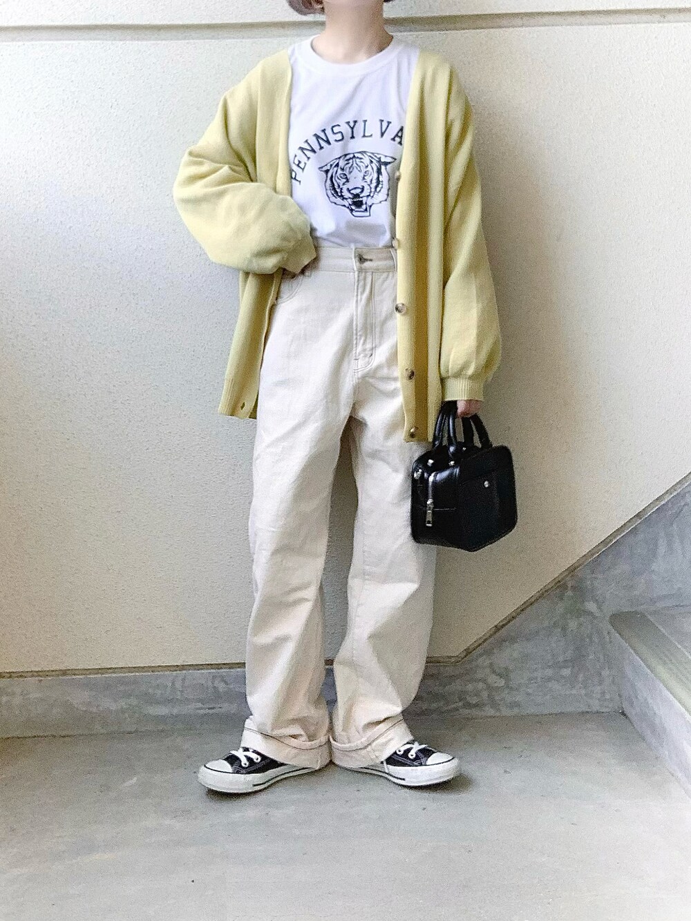 イエロー系のカーディガン/ボレロ、ホワイト系のTシャツ/カットソー、ホワイト系のデニムパンツを着用したレディースの冬コーディネートの1枚目の写真