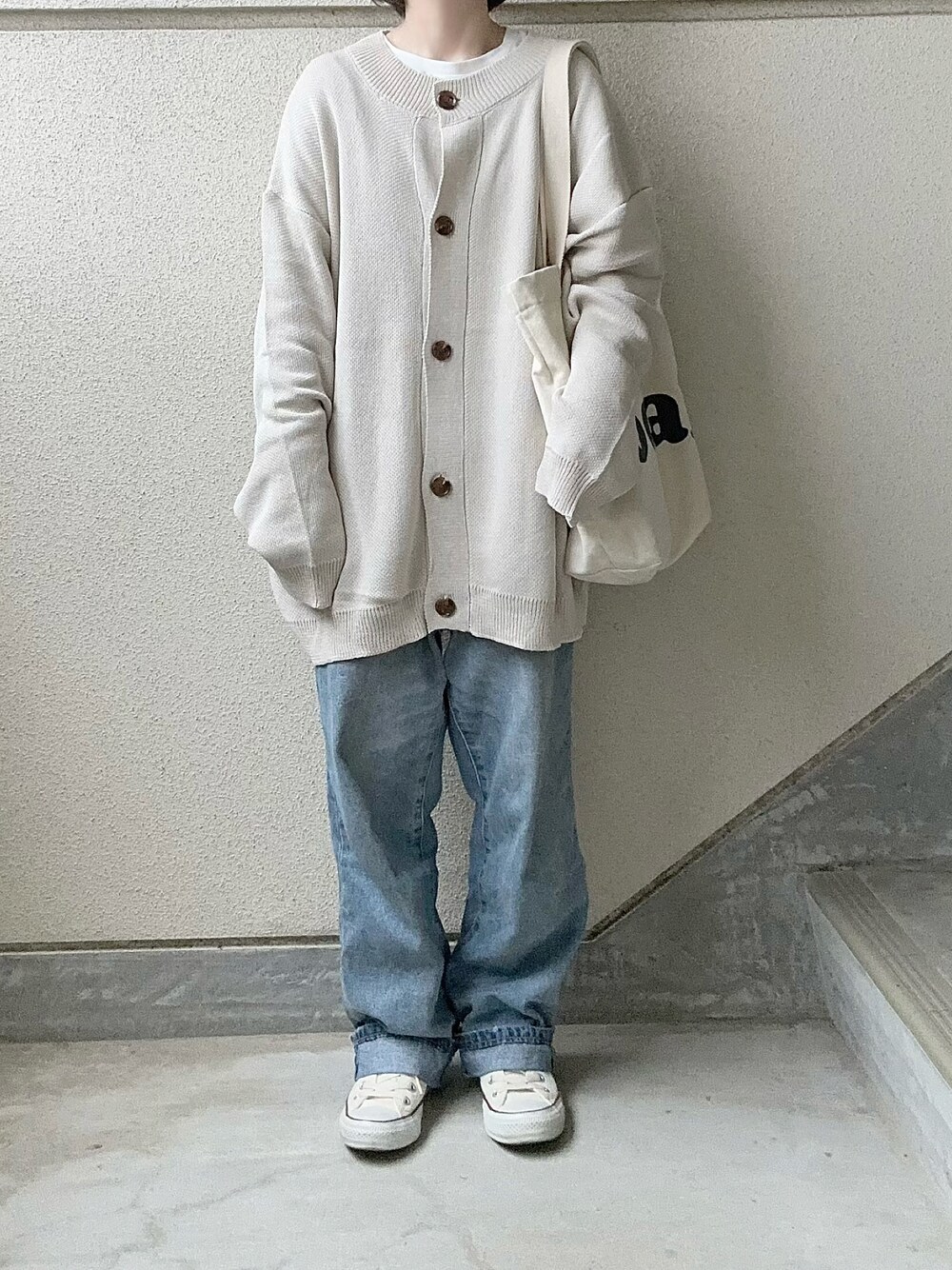 ベージュ系のカーディガン/ボレロ、ブルー系のデニムパンツ、ホワイト系のスニーカーを着用したレディースの冬コーディネートの1枚目の写真