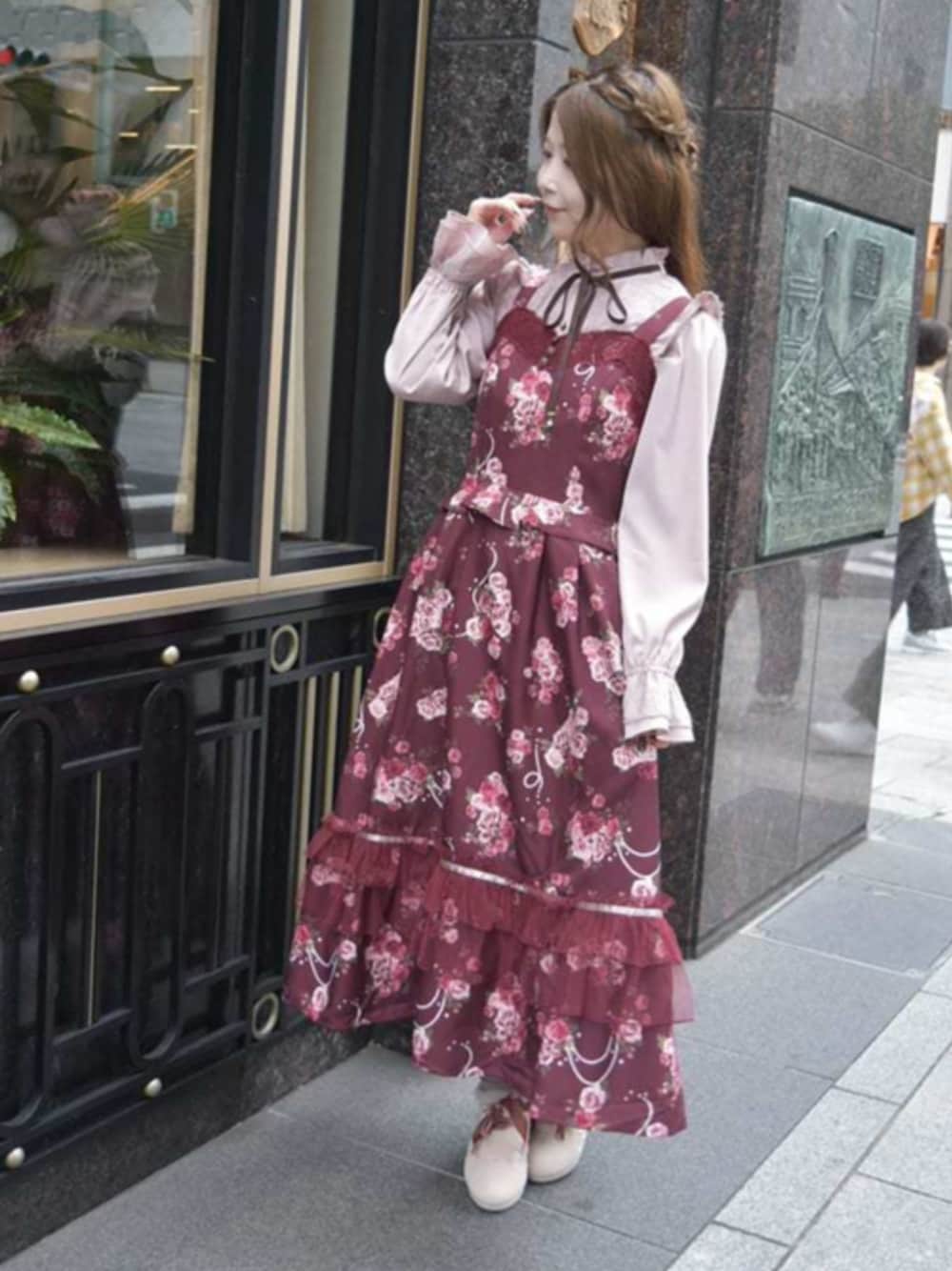 ピンク系のシャツ/ブラウス、ブラック系のブーツ、レッド系のジャンパースカートを着用したレディースの秋コーディネートの1枚目の写真