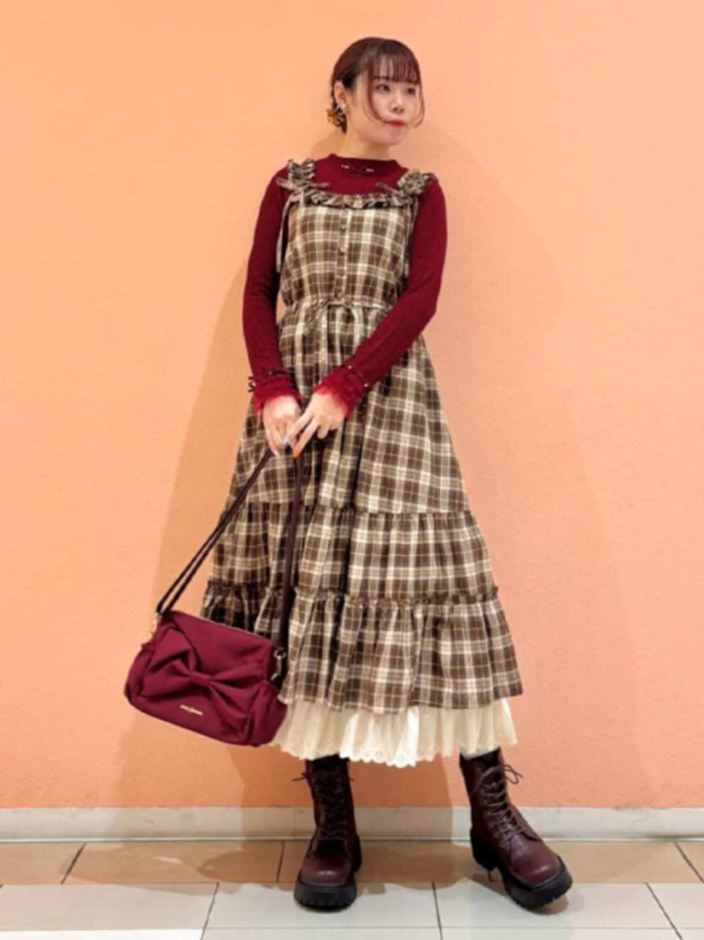 レッド系のショルダーバッグ、レッド系のTシャツ/カットソー、ブラウン系のワンピースを着用したレディースの秋コーディネートの1枚目の写真