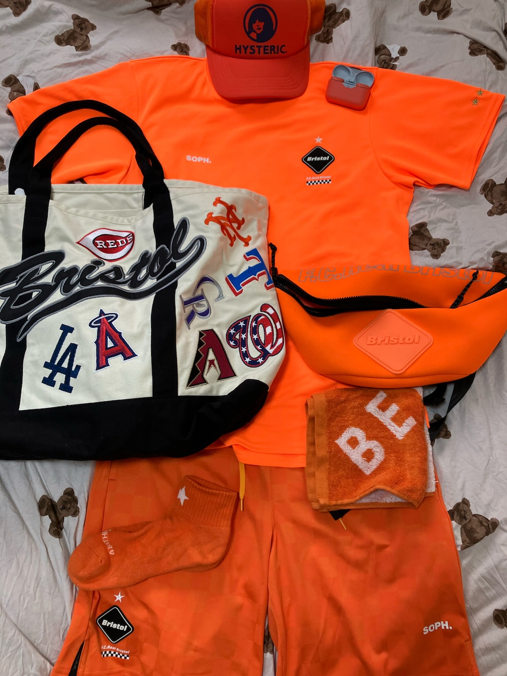 オレンジ系のTシャツ/カットソー、ホワイト系のトートバッグ、オレンジ系のボディバッグ/ウエストポーチを着用したメンズの夏コーディネートの1枚目の写真