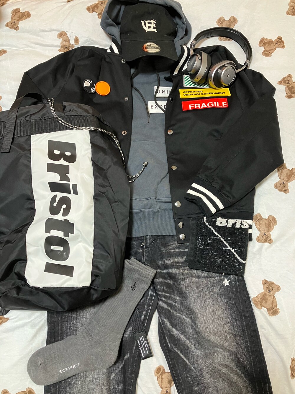 「uniform experiment、スタジャン×パーカー、モノトーン、ハンドタオルは手放せない、お布団乗せ乗せコーデ、低身長、極端な若作り、ベースボールキャップ、ヘッドフォン、Master&dynamic」｜「uniform experimentのSTADIUM BLOUSON（ブルゾン、ブラック系）」を使った、名和 賢悟さん（メンズ・159cm）の春コーディネートの1枚目の写真