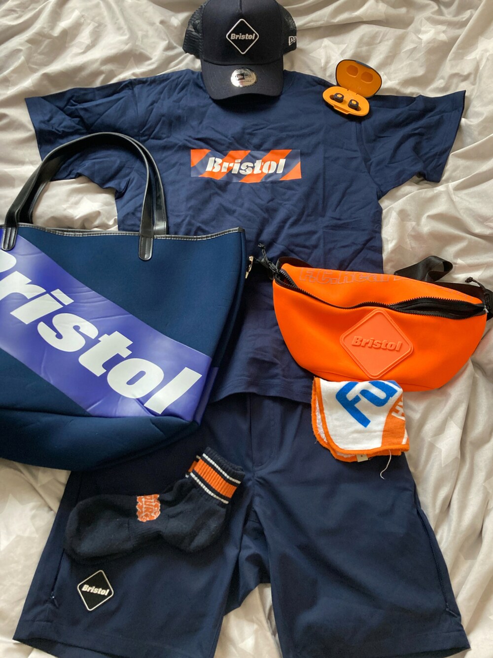 ブルー系のTシャツ/カットソー、ブルー系のトートバッグ、オレンジ系のボディバッグ/ウエストポーチを着用したメンズの夏コーディネートの1枚目の写真