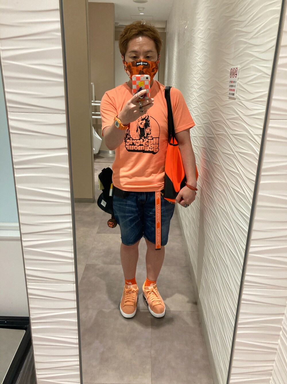 オレンジ系のTシャツ/カットソー、オレンジ系のトートバッグ、ブルー系のデニムパンツを着用したメンズの夏コーディネートの1枚目の写真