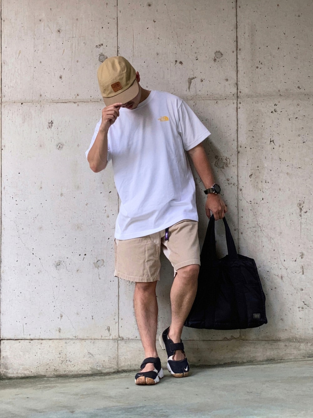 イエロー系のTシャツ/カットソー、ベージュ系のパンツ、ブラック系のトートバッグを着用したメンズの夏コーディネートの1枚目の写真