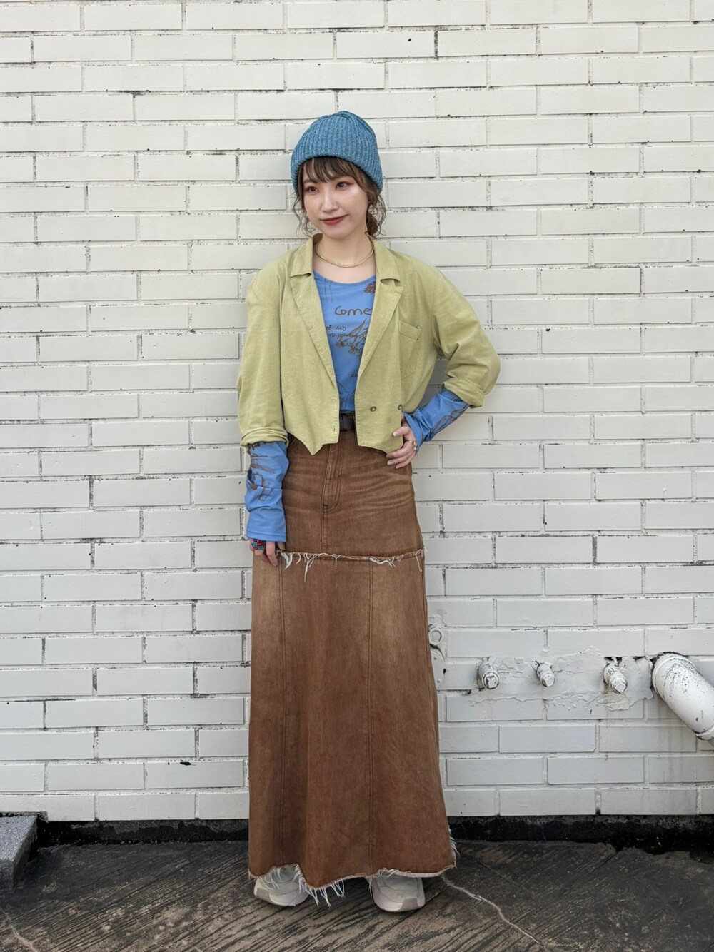 グリーン系のジャケット/アウター、ブラウン系のデニムスカート、ベージュ系のスニーカーを着用したレディースの春コーディネートの1枚目の写真