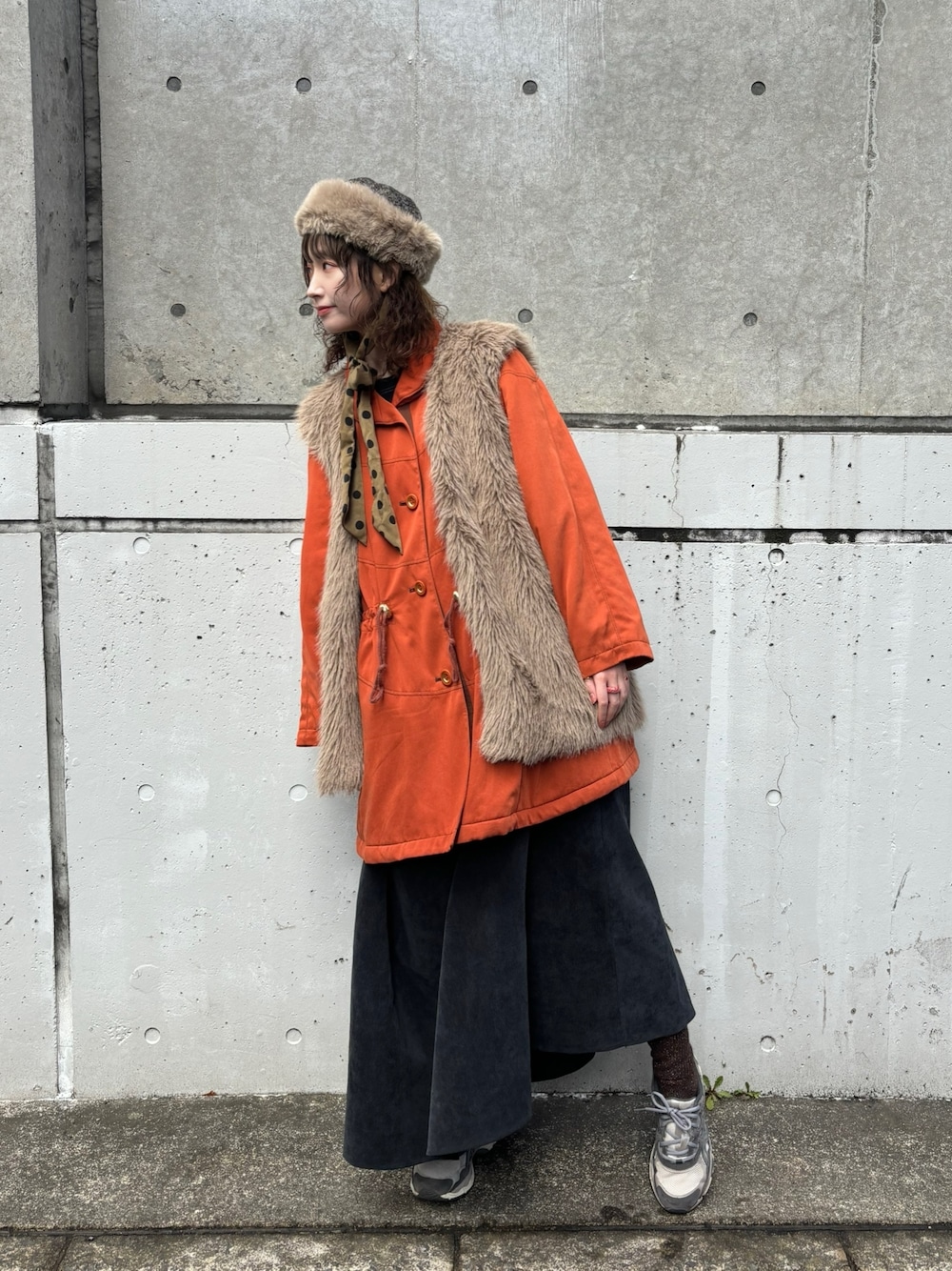 ベージュ系のベスト、オレンジ系のジャケット/アウター、ブラック系のワンピースを着用したレディースの春コーディネートの1枚目の写真