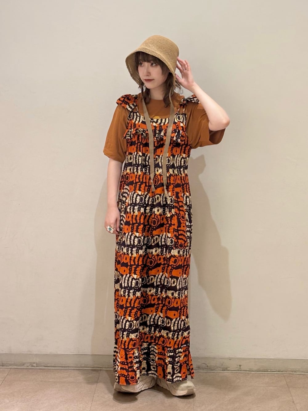 オレンジ系のワンピース/ドレス、ブラウン系のTシャツ/カットソー、ベージュ系のスニーカーを着用したレディースの夏コーディネートの1枚目の写真