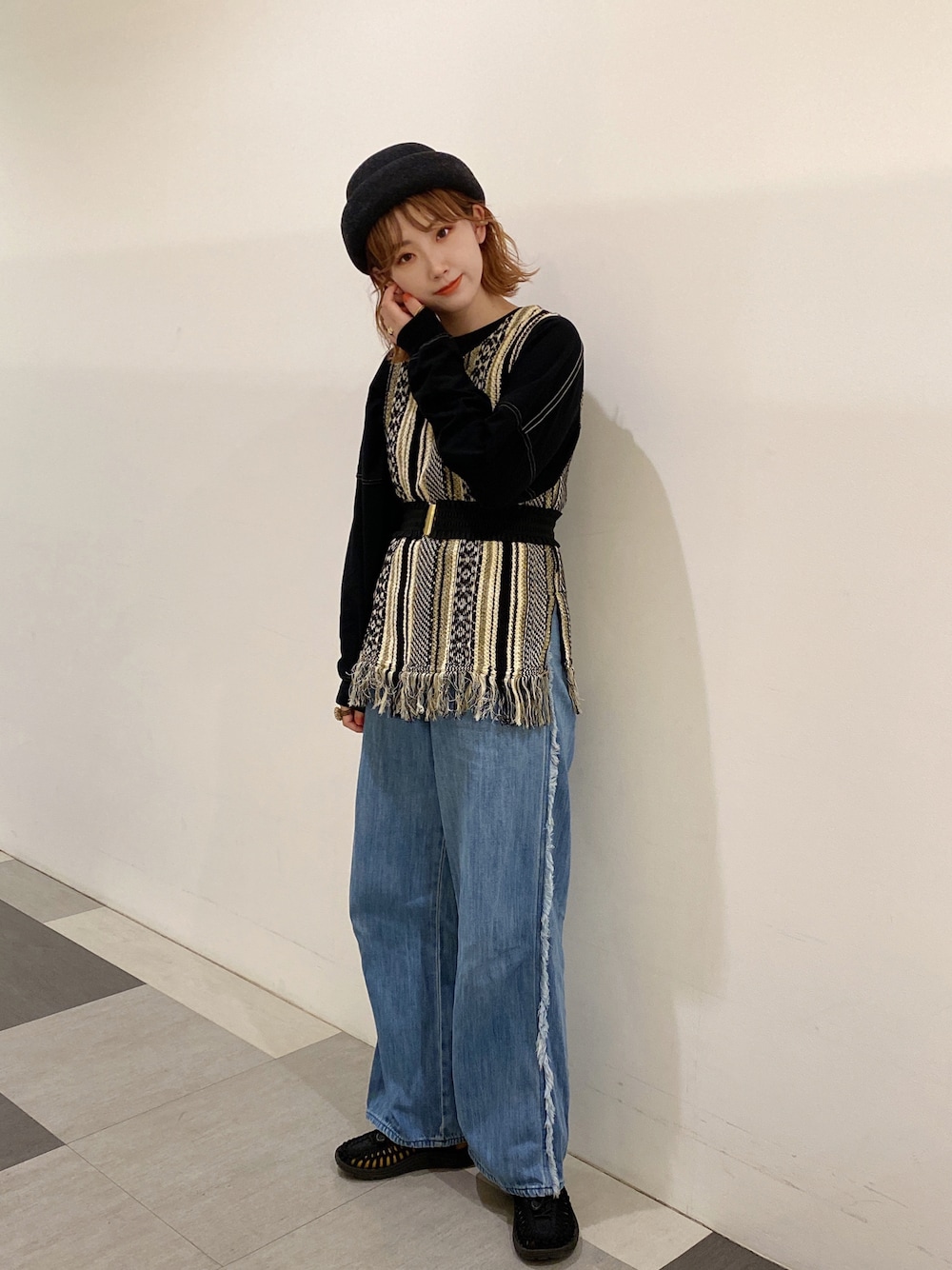 ブルー系のデニムパンツ、ブラック系のサンダル、ブラック系のベストを着用したレディースの秋コーディネートの1枚目の写真