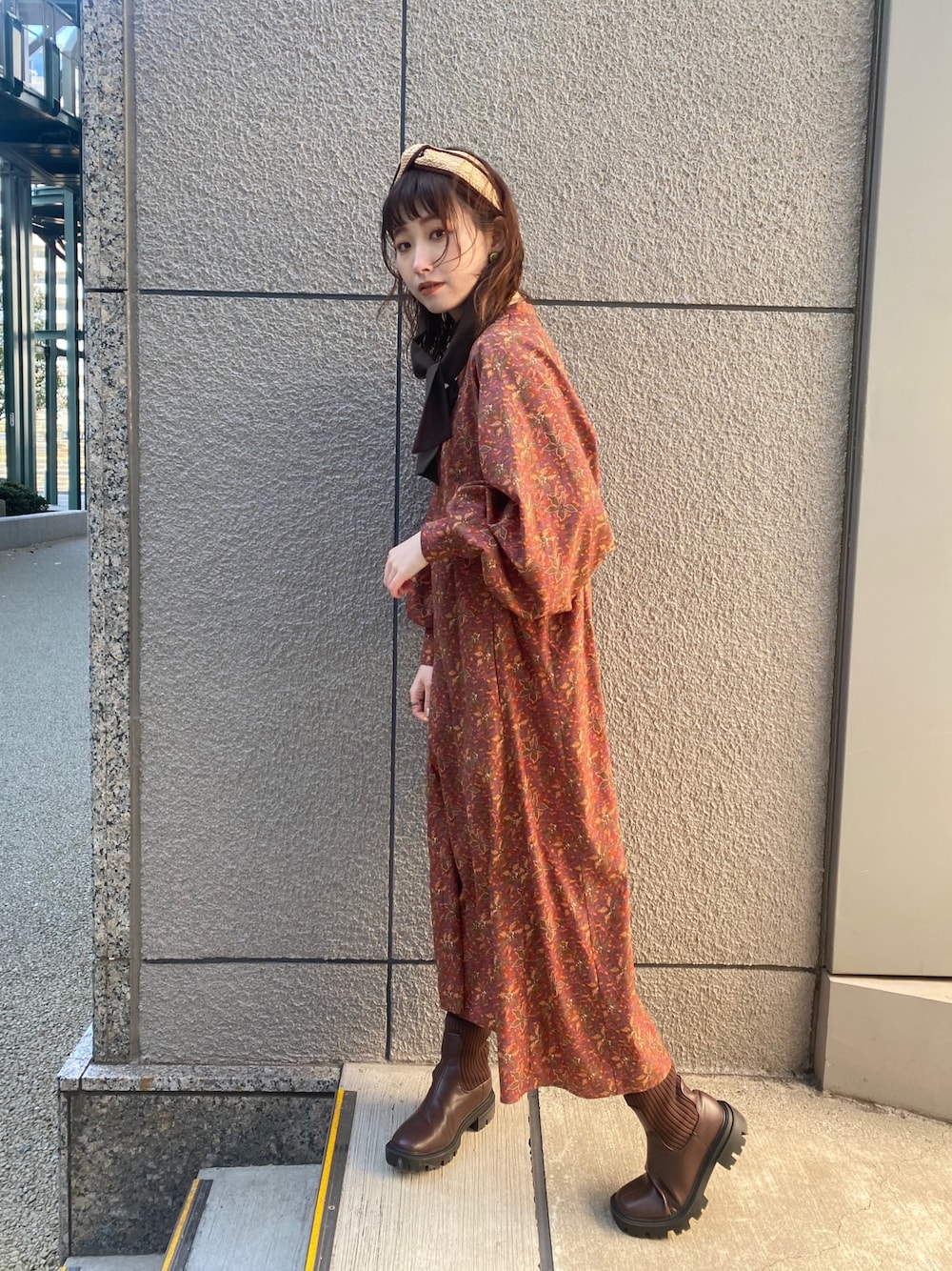オレンジ系のワンピース、ブラウン系のブーツ、ブラウン系のカチューシャを着用したレディースの冬コーディネートの1枚目の写真