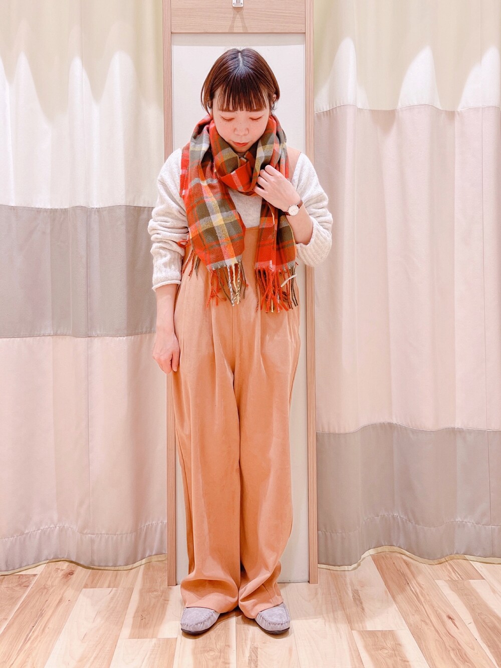 ホワイト系のニット/セーター、オレンジ系のサロペット/オーバーオール、グレー系のモカシン/デッキシューズを着用したレディースの冬コーディネートの1枚目の写真