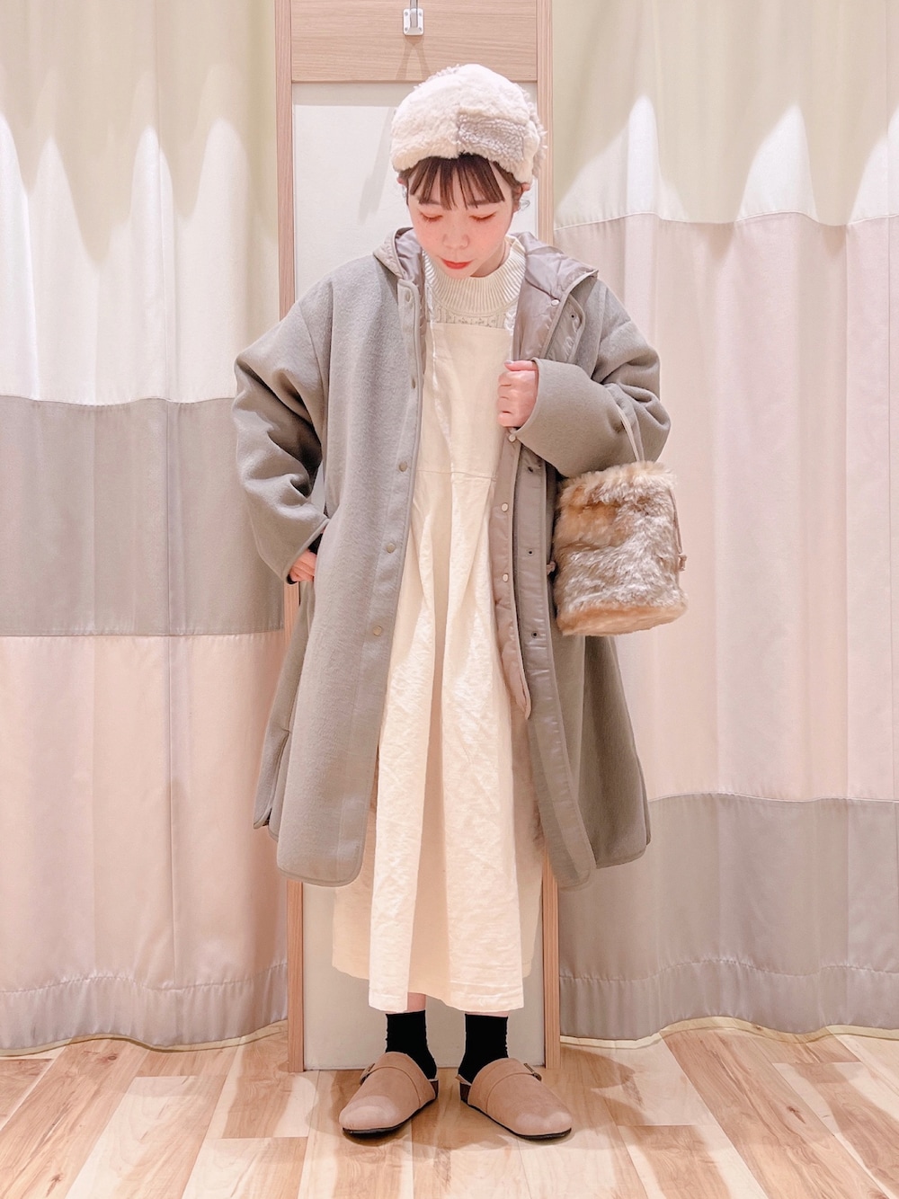 ホワイト系のジャンパースカート、ブラウン系のその他アウター、ベージュ系のサンダルを着用したレディースの秋コーディネートの1枚目の写真