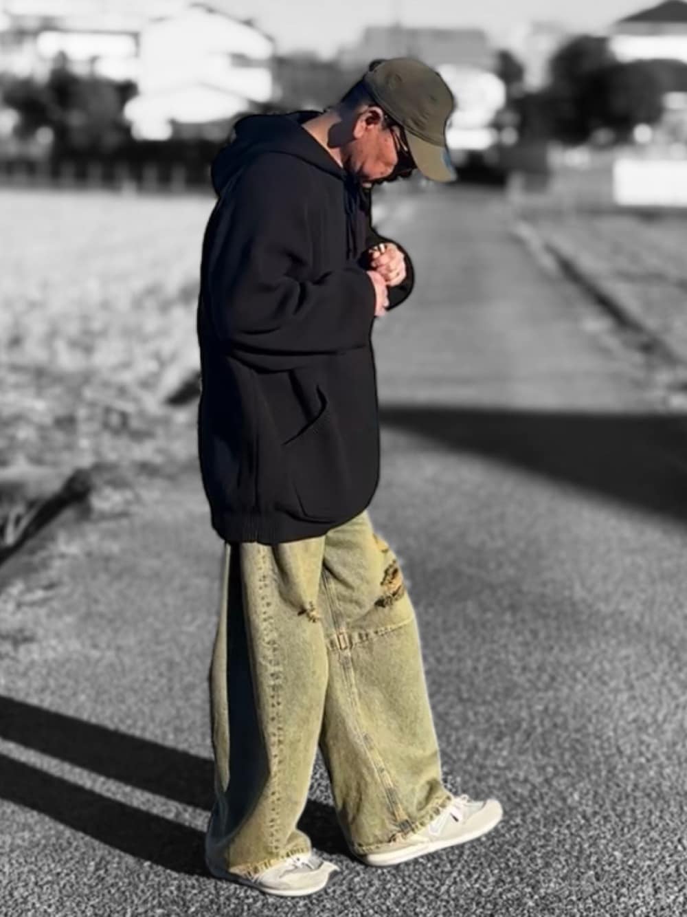 ブルー系のデニムパンツ、ブラック系のパーカー、ブラウン系のキャップを着用したメンズの冬コーディネートの1枚目の写真