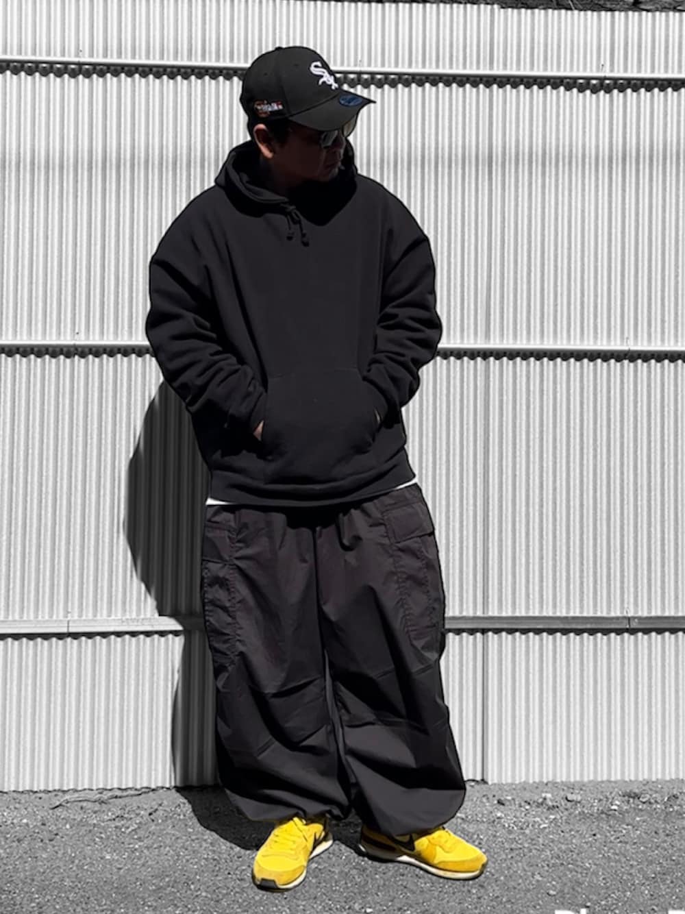 ブラック系のパーカー、ブラック系のカーゴパンツ、ブラック系のキャップを着用したメンズの冬コーディネートの1枚目の写真