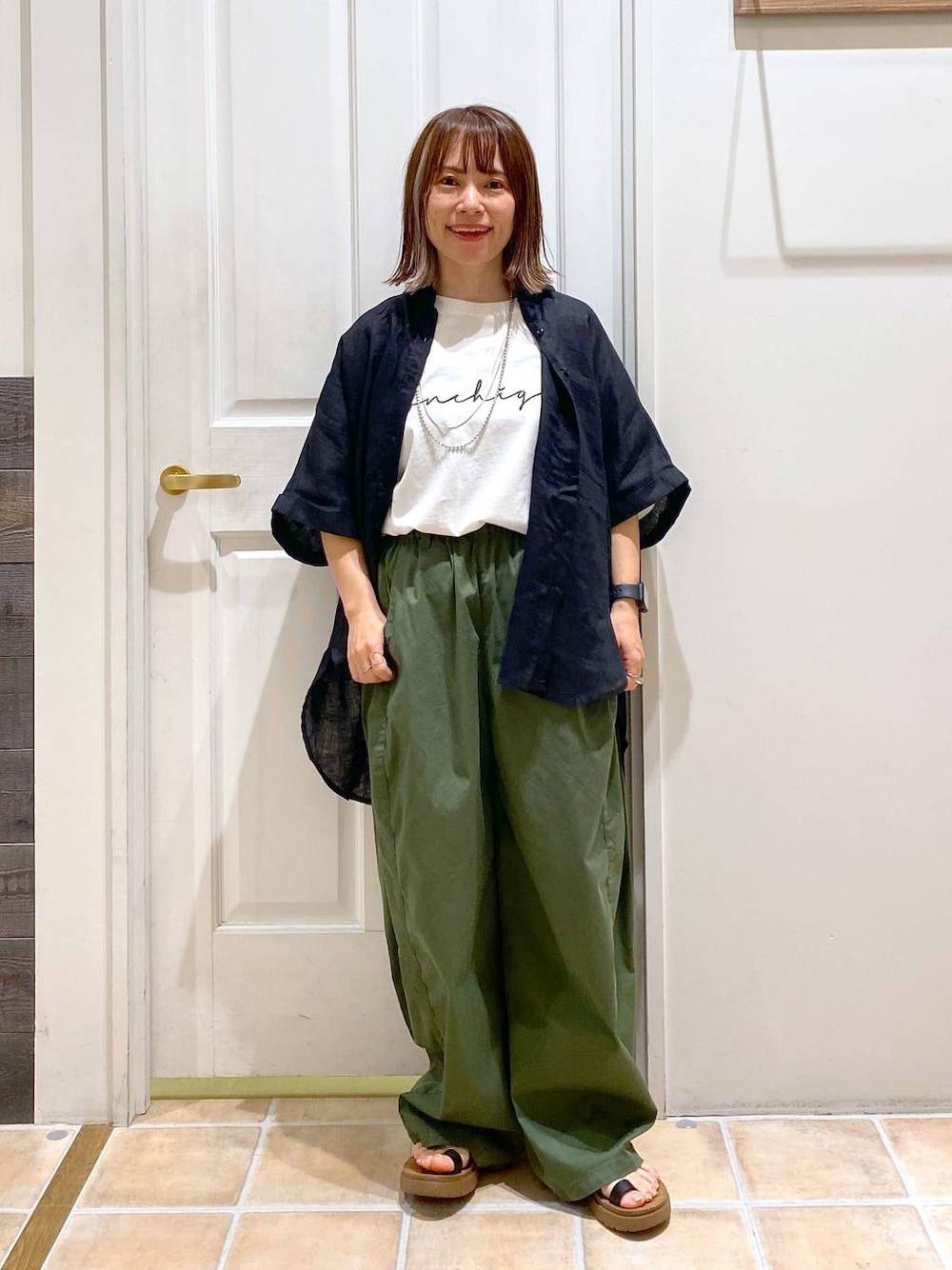 ブラック系のサンダル、ブラック系のシャツ/ブラウス、その他のTシャツ/カットソーを着用したレディースの夏コーディネートの1枚目の写真