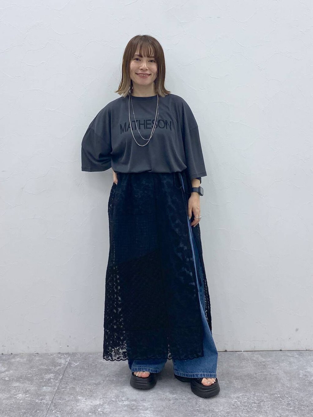 ブラック系のサンダル、ブルー系のデニムパンツ、ブラック系のスカートを着用したレディースの秋コーディネートの1枚目の写真