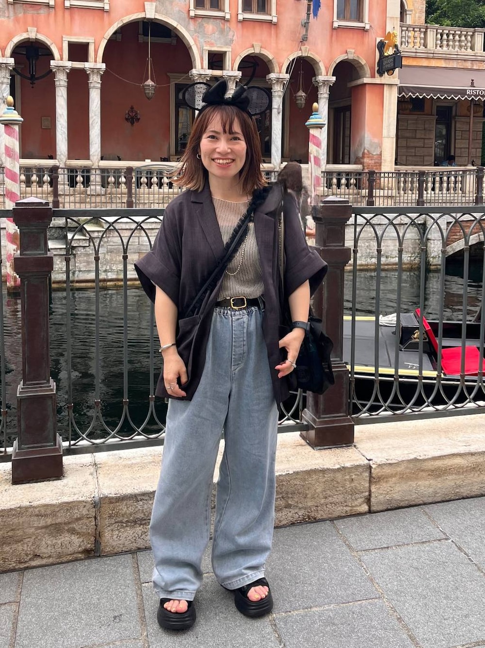 ブラック系のサンダル、ブルー系のデニムパンツ、グレー系のテーラードジャケットを着用したレディースの夏コーディネートの1枚目の写真