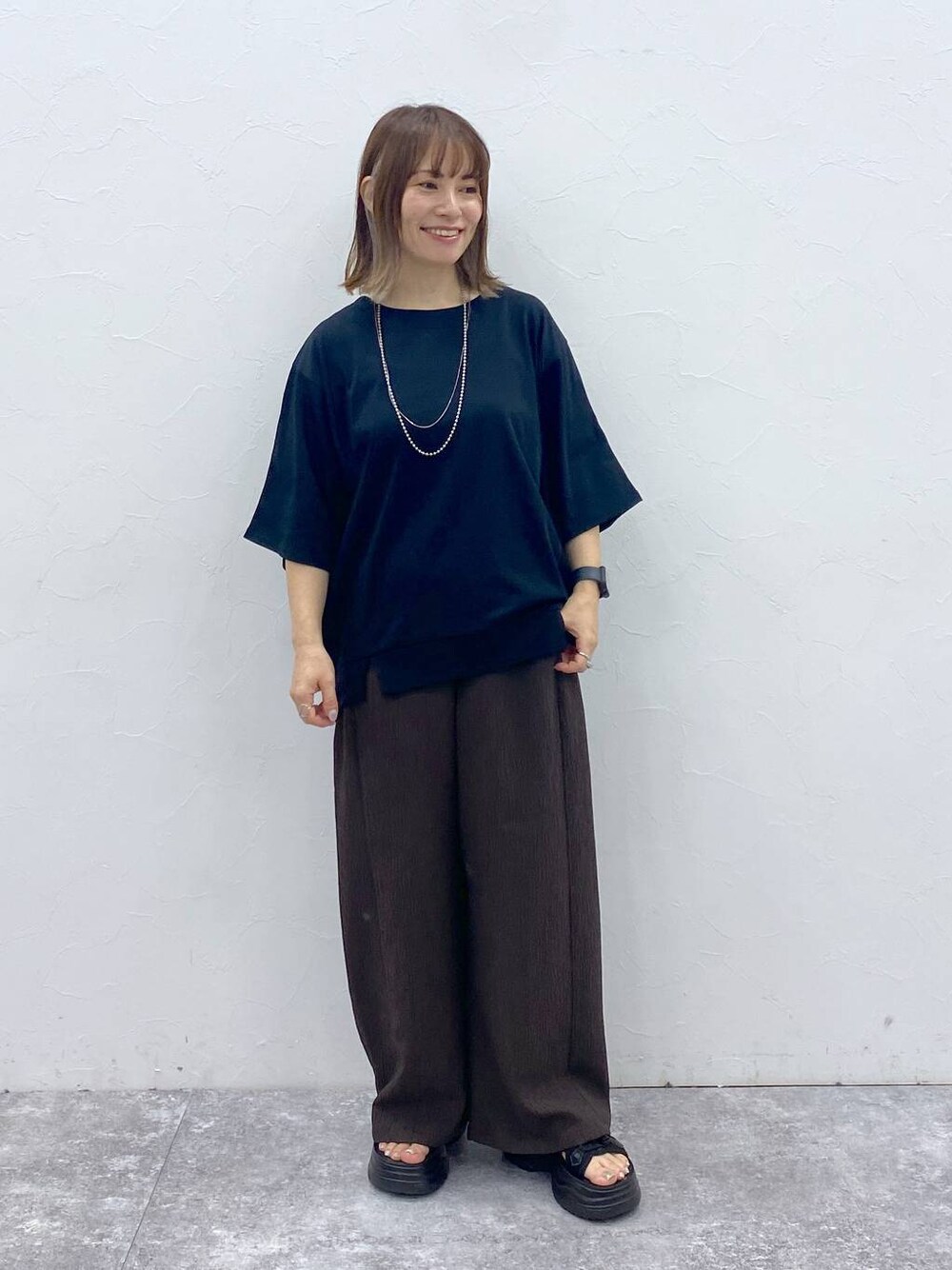 ブラック系のサンダルを着用したレディースの夏コーディネートの1枚目の写真