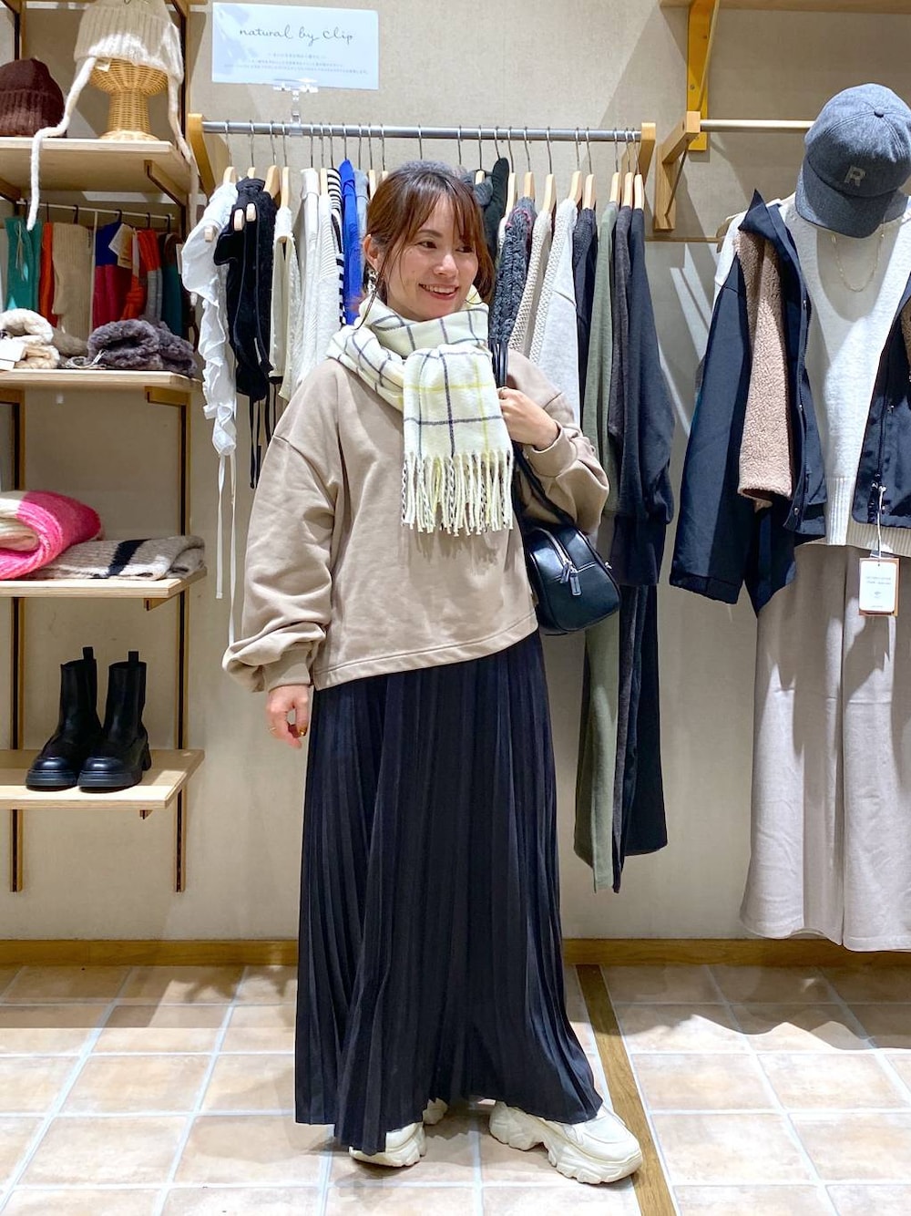 グレー系のスカート、ブラック系のトートバッグ、ベージュ系のTシャツ/カットソーを着用したレディースの冬コーディネートの1枚目の写真