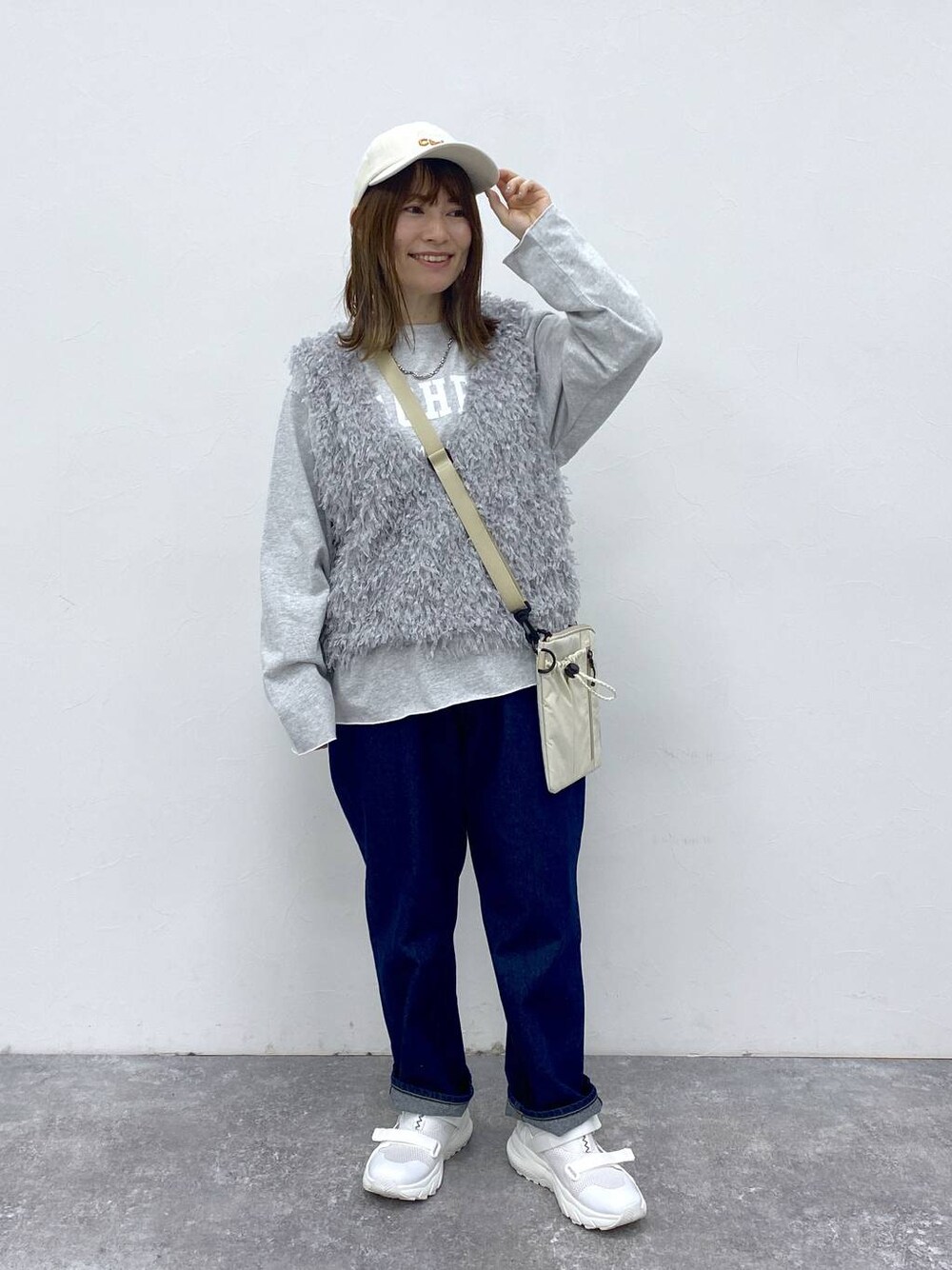 ブルー系のデニムパンツ、グレー系のベスト、グレー系のTシャツ/カットソーを着用したレディースの春コーディネートの1枚目の写真