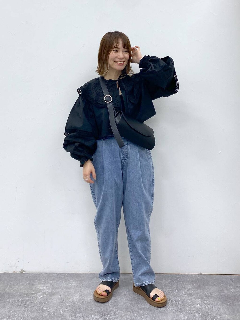 ブラック系のサンダル、ブルー系のデニムパンツ、ブラック系のショルダーバッグを着用したレディースの夏コーディネートの1枚目の写真