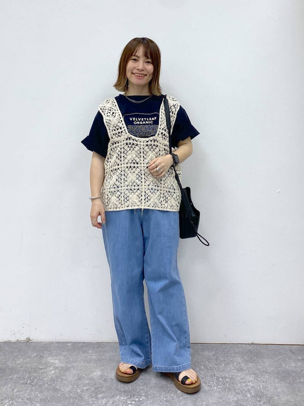 ブラック系のサンダル、ブルー系のデニムパンツ、ブラック系のショルダーバッグを着用したレディースの春コーディネートの1枚目の写真