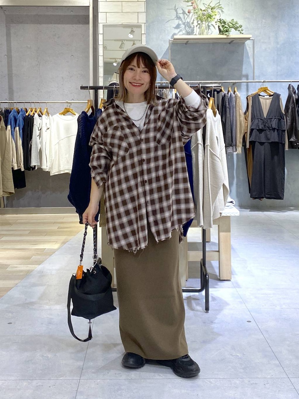 ブラック系のショルダーバッグ、ブラウン系のスカート、ブラック系のスニーカーを着用したレディースの秋コーディネートの1枚目の写真