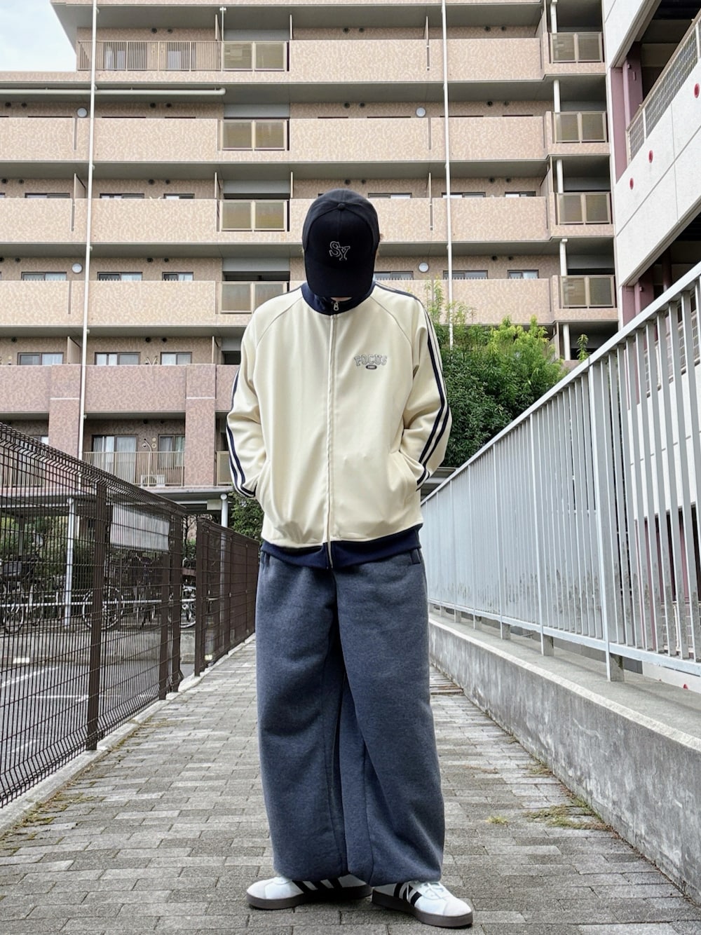 ホワイト系のスニーカー、ホワイト系のブルゾン、グレー系のスウェットパンツを着用したメンズの秋コーディネートの1枚目の写真