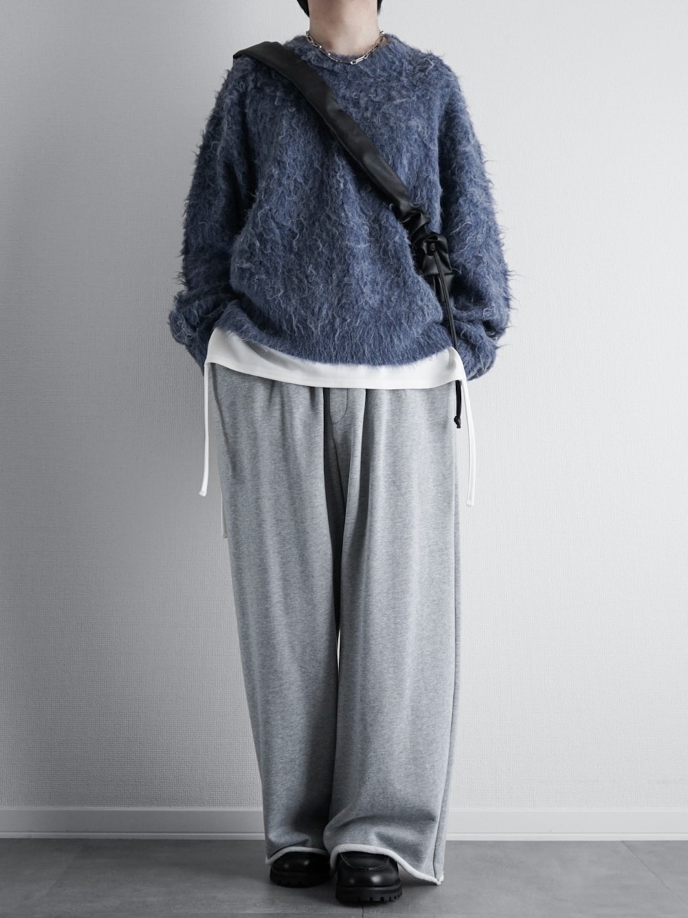 グレー系のニット/セーター、ホワイト系のタンクトップ、グレー系のスウェットパンツを着用したメンズの秋コーディネートの1枚目の写真