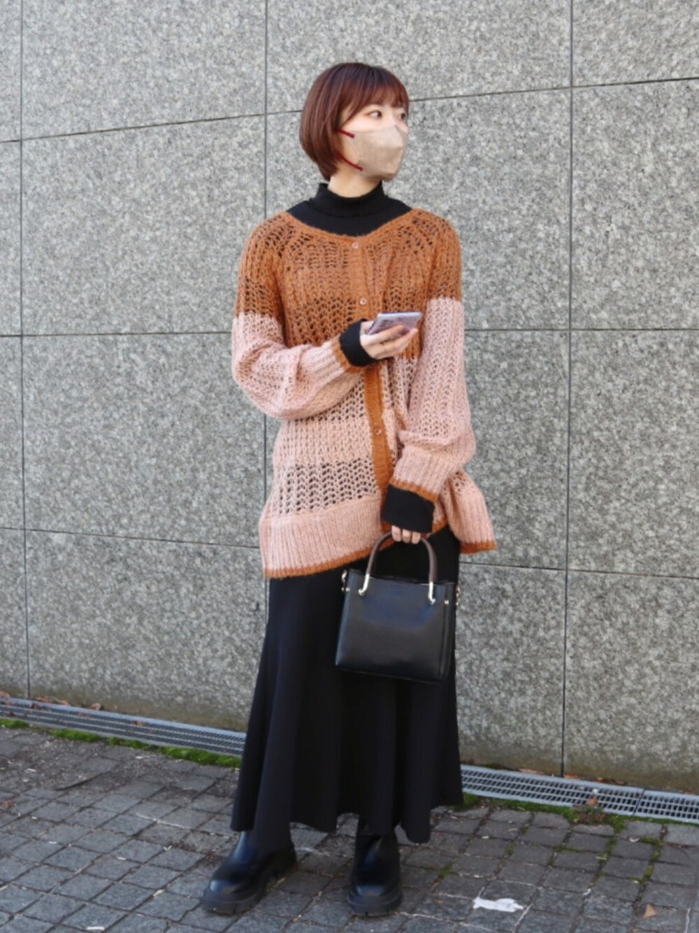 ブラウン系のニット/セーター、ホワイト系のTシャツ/カットソー、ブラック系のスカートを着用したレディースの冬コーディネートの1枚目の写真
