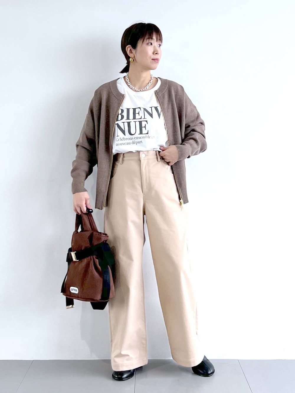 ブラウン系のショルダーバッグ、ホワイト系のTシャツ/カットソー、ブラック系のブーツを着用したレディースの秋コーディネートの1枚目の写真