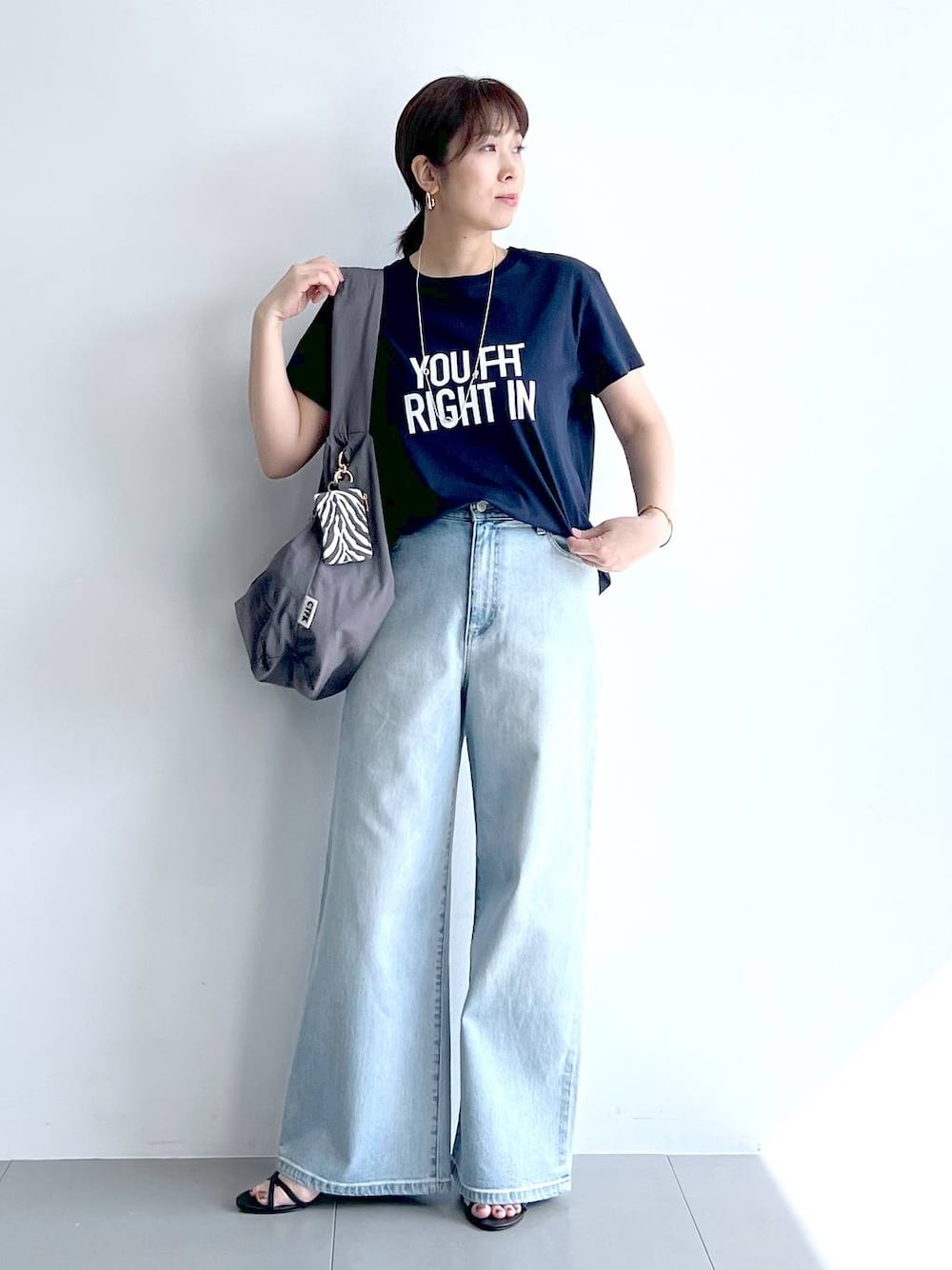ブルー系のデニムパンツ、グレー系のショルダーバッグ、ブラック系のサンダルを着用したレディースの夏コーディネートの1枚目の写真