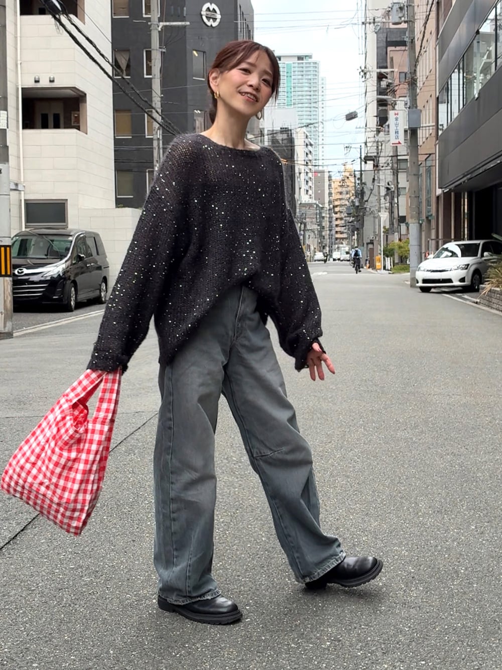 ブラック系のニット/セーター、ブルー系のデニムパンツ、レッド系のエコバッグ/サブバッグを着用したレディースの秋コーディネートの1枚目の写真