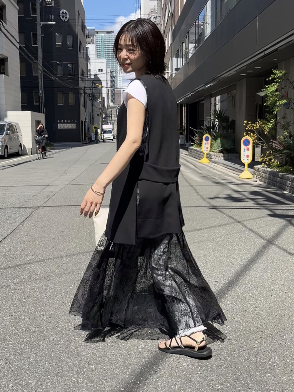 ブラック系のワンピース、ブラック系のサンダル、ブラック系のベストを着用したレディースの夏コーディネートの1枚目の写真