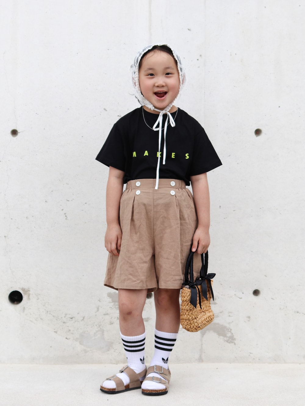 ベージュ系のその他パンツ、ベージュ系のサンダル、ブラック系のTシャツ/カットソーを着用したキッズの夏コーディネートの1枚目の写真
