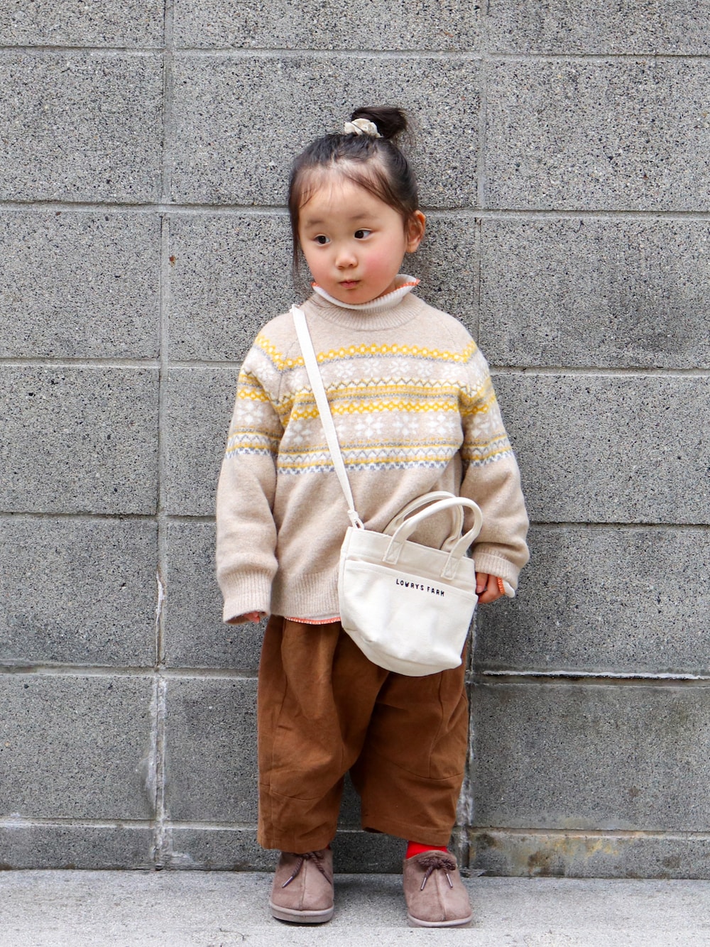 ベージュ系のニット/セーター、ホワイト系のTシャツ/カットソー、ブラウン系のチノパンツを着用したキッズの冬コーディネートの1枚目の写真