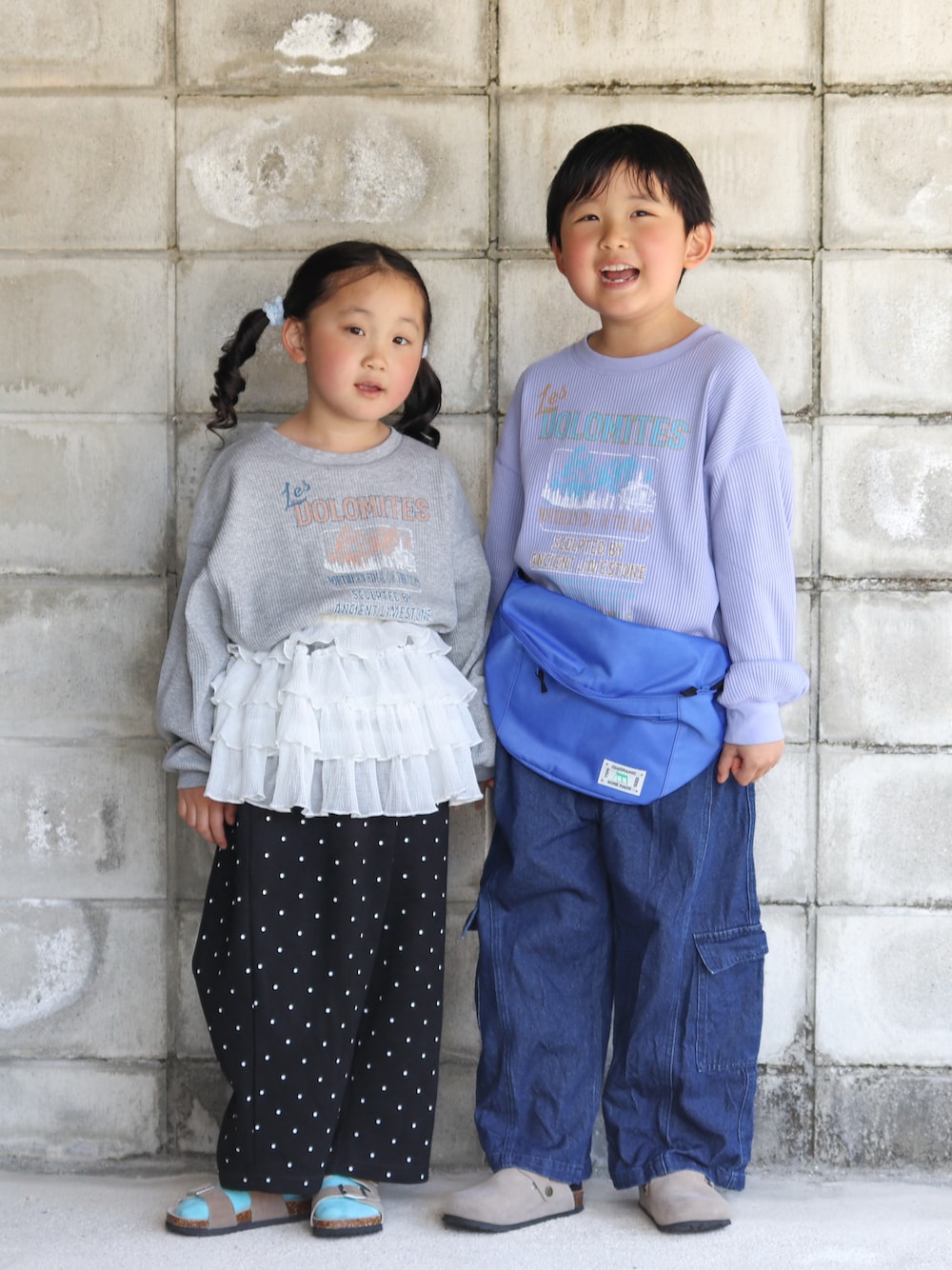 ブルー系のカーゴパンツ、ブルー系のボディバッグ/ウエストポーチ、ベージュ系のサンダルを着用したキッズの春コーディネートの1枚目の写真