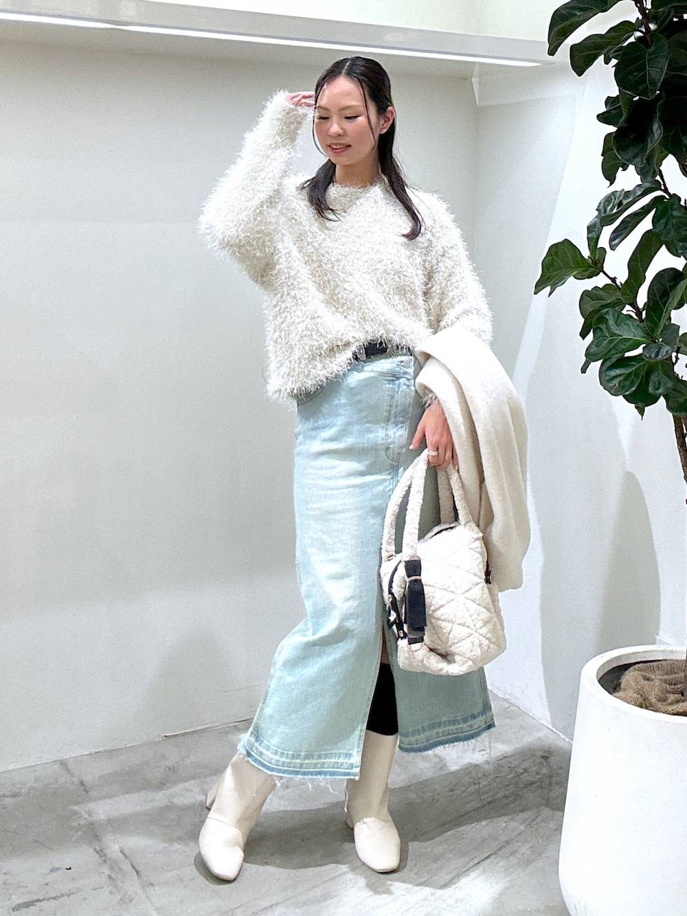 ブルー系のデニムスカート、ベージュ系のブーツ、ホワイト系のショルダーバッグを着用したレディースの冬コーディネートの1枚目の写真
