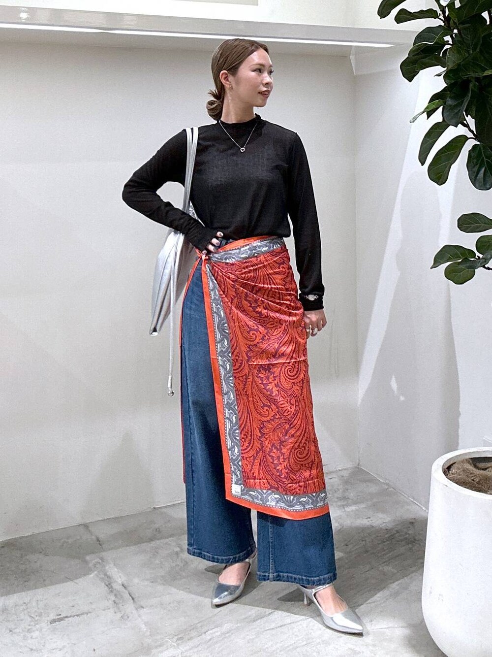 シルバー系のパンプス、ブラック系のTシャツ/カットソー、ブルー系のデニムパンツを着用したレディースの冬コーディネートの1枚目の写真