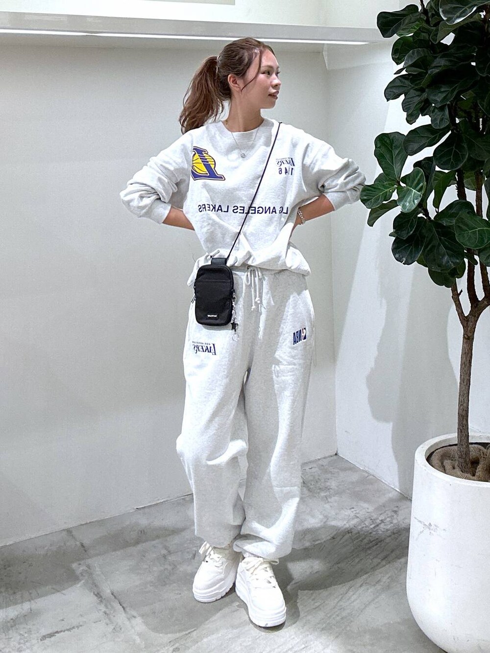 ホワイト系のスニーカー、グレー系のスウェットパンツ、ブラック系のショルダーバッグを着用したレディースの秋コーディネートの1枚目の写真