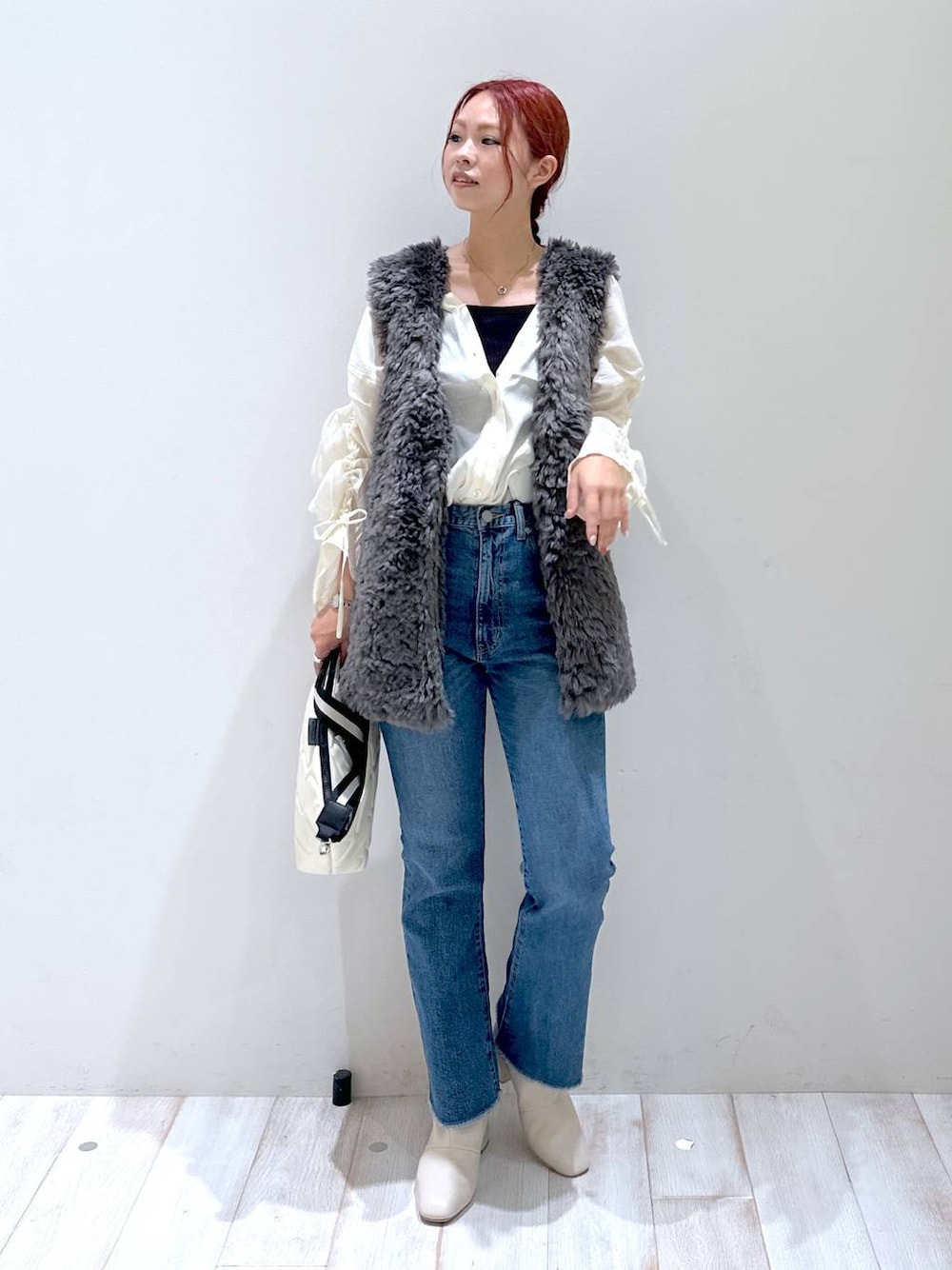 ベージュ系のショルダーバッグ、ホワイト系のシャツ/ブラウス、ブルー系のデニムパンツを着用したレディースの秋コーディネートの1枚目の写真