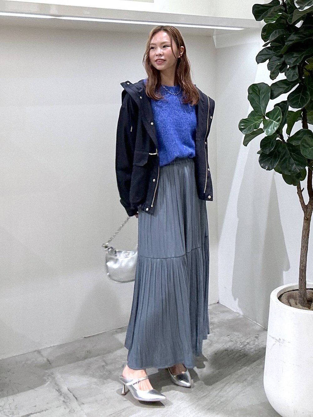 ブルー系のマウンテンパーカー、シルバー系のショルダーバッグ、ブルー系のスカートを着用したレディースの秋コーディネートの1枚目の写真