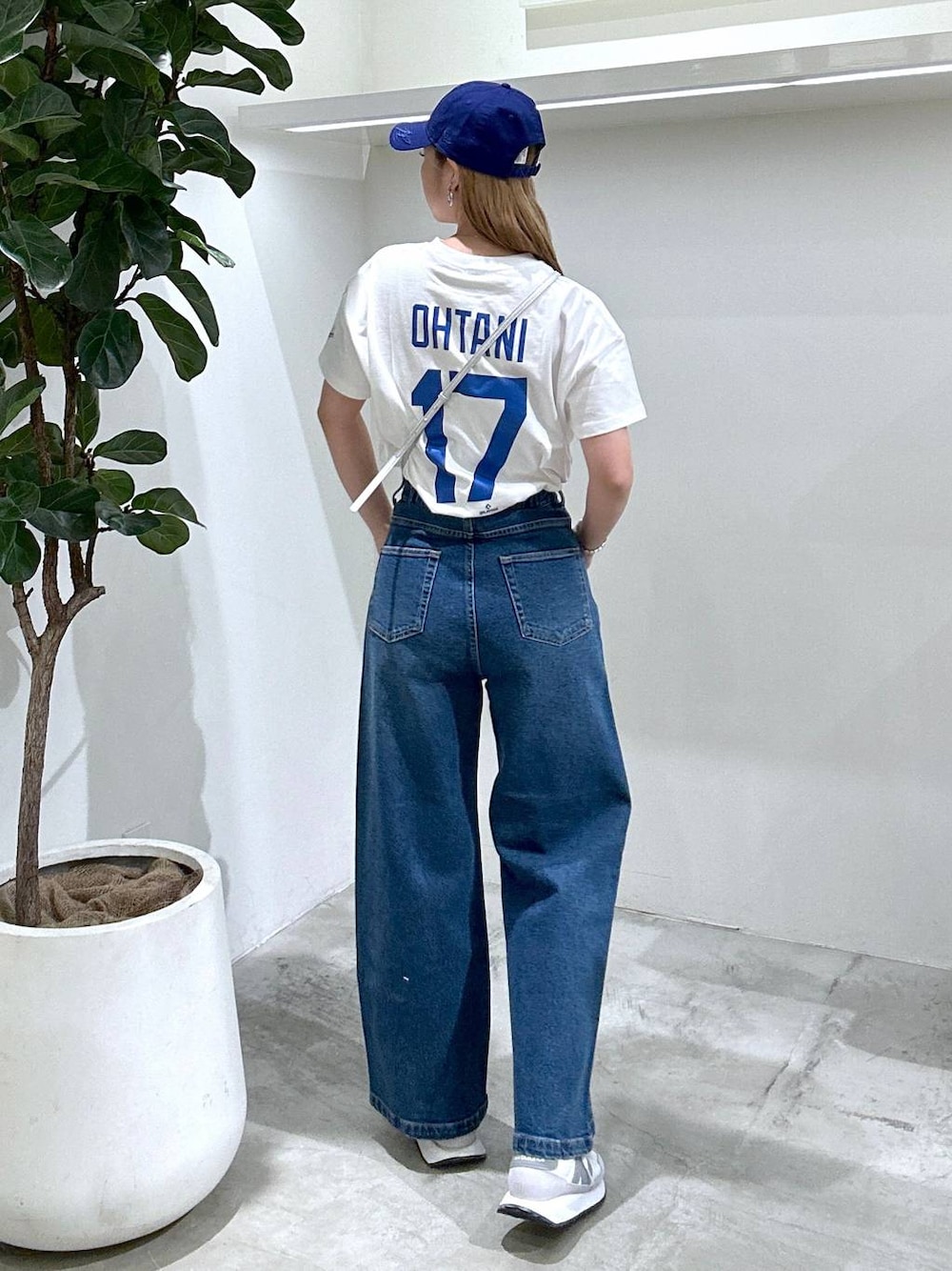 ブルー系のデニムパンツ、ホワイト系のスニーカー、ホワイト系のTシャツ/カットソーを着用したレディースの春コーディネートの1枚目の写真