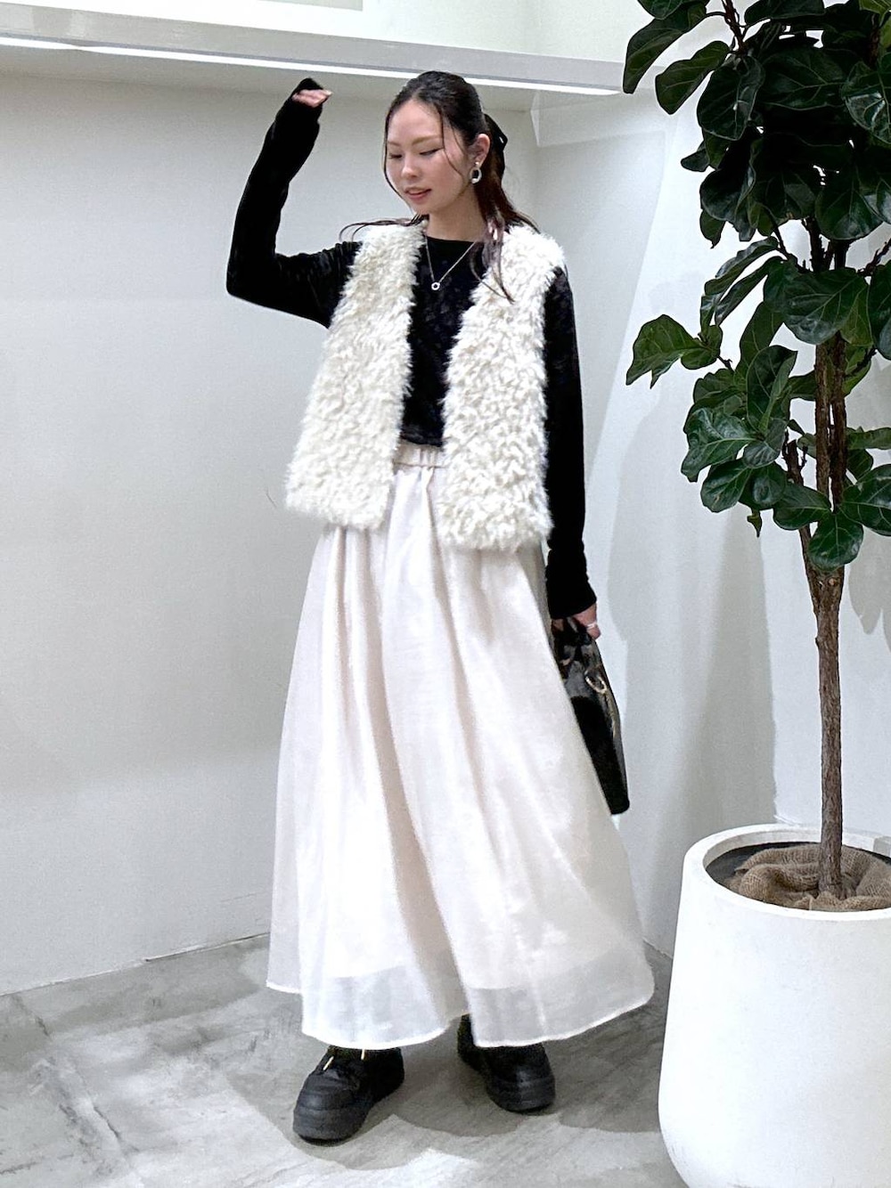 ブラック系のスニーカー、ブラック系のハンドバッグ、ベージュ系のスカートを着用したレディースの冬コーディネートの1枚目の写真